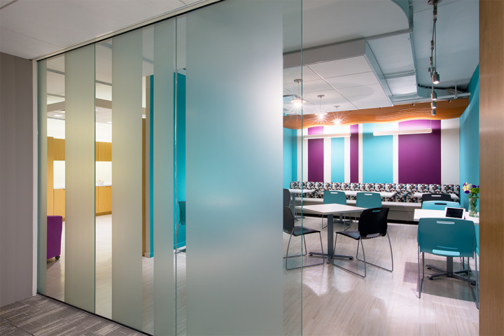 Bold painted stripes of turquoise and eggplant, accentuates the banquette’s dynamic fabric, giving the lounge a café like feel. Small tables and colorful chairs fill the space and exposed ceilings and floating elements, takes advantage of the higher ceilings, while keeping acoustics in mind. Image courtesy of BBGM.