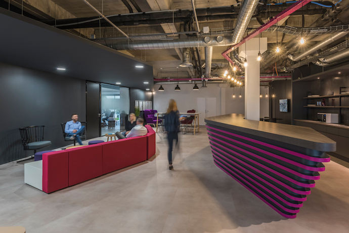 Blending an industrial feel with angular joinery and modular furniture, the space is also wrapped in dark timber, highlighted by vibrant colour and pendant lighting selections. Image courtesy of Airbus.
