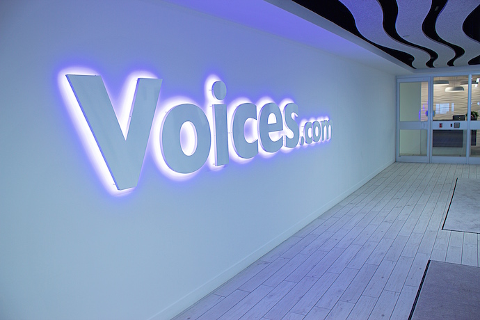 The Voices.com logo greets employees and visitors as they get off the elevator while sound waves along the ceiling guide you into the office. Image courtesy of In Design Associates. 