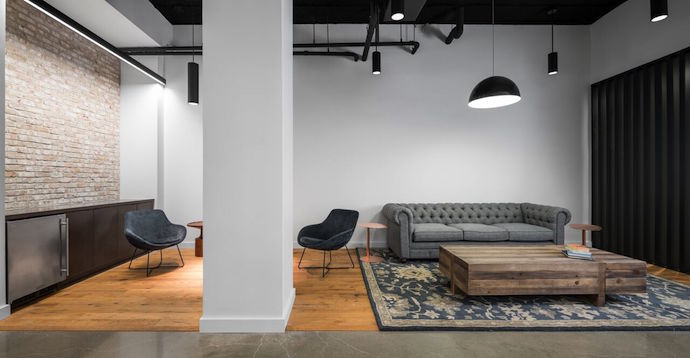 lauckgroup designed a welcoming entry area with a hospitality bar, soft seating, an aged brick accent wall, wood flooring and a hand-woven rug exude a professional yet relaxed ambience. Image courtesy of Peter Molick.