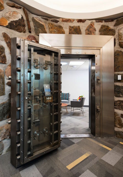 The “doughnut-shape” bank vault, seen as the distinctive, round, stone-clad wall on the exterior, is another one of the office's more dramatic features. Image courtesy of Cuningham Group Architecture.